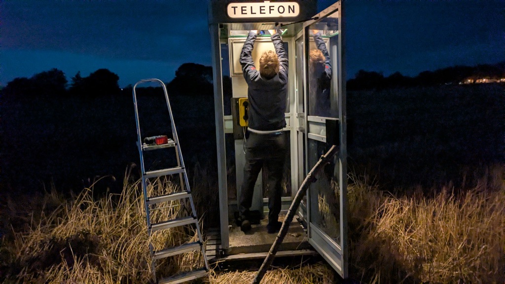 Someone reaching up to fit the light inside the booth at dusk