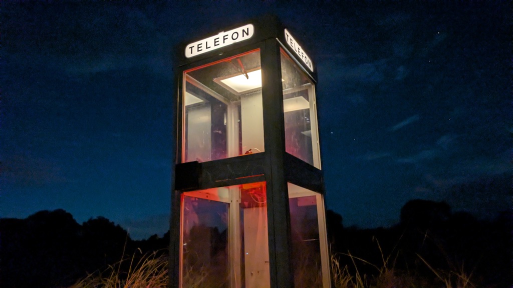 The booth lit against the night sky in the field