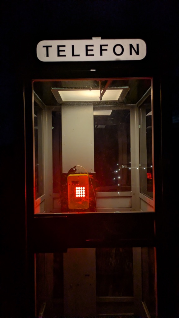 The lit TELEFON sign above the glowing yellow handset
